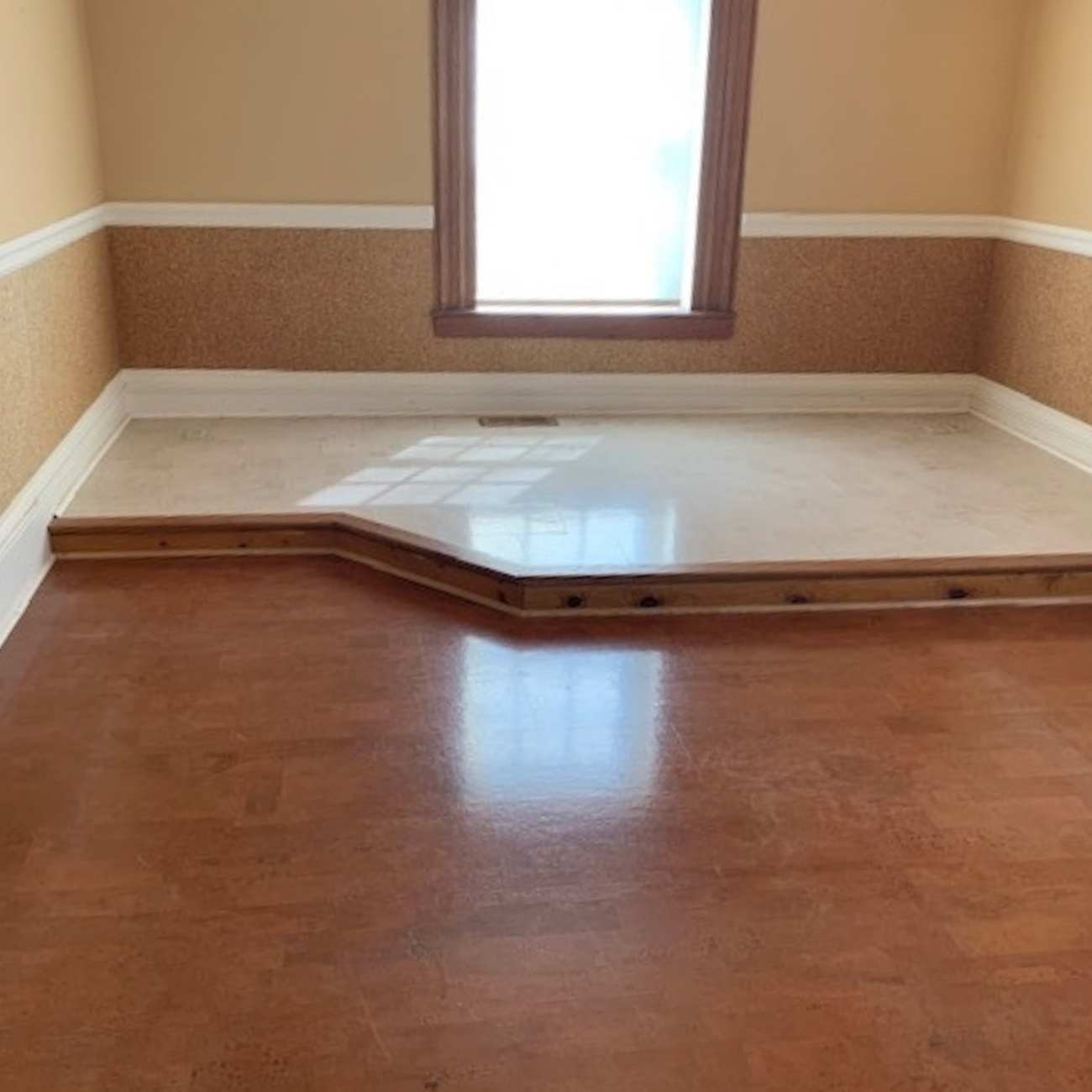Harmony Brown Cork flooring installed in an empty room with a raised platform with a lighter, custom cork flooring on the platform
