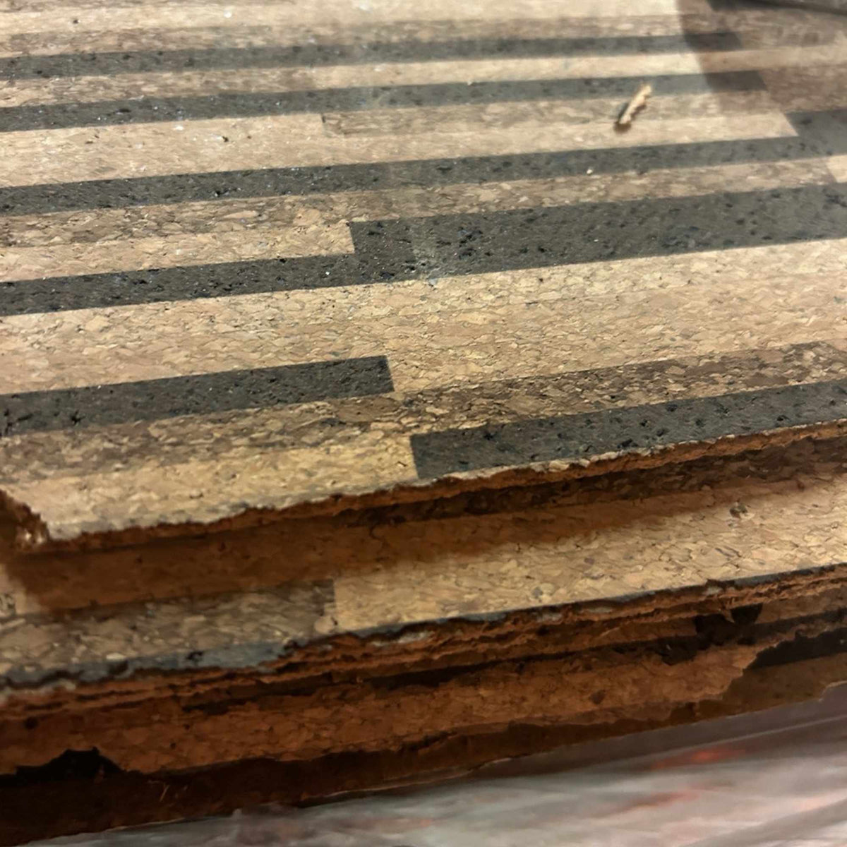 Side view of stacked Rio XL cork tiles showing rough, untrimmed edges.