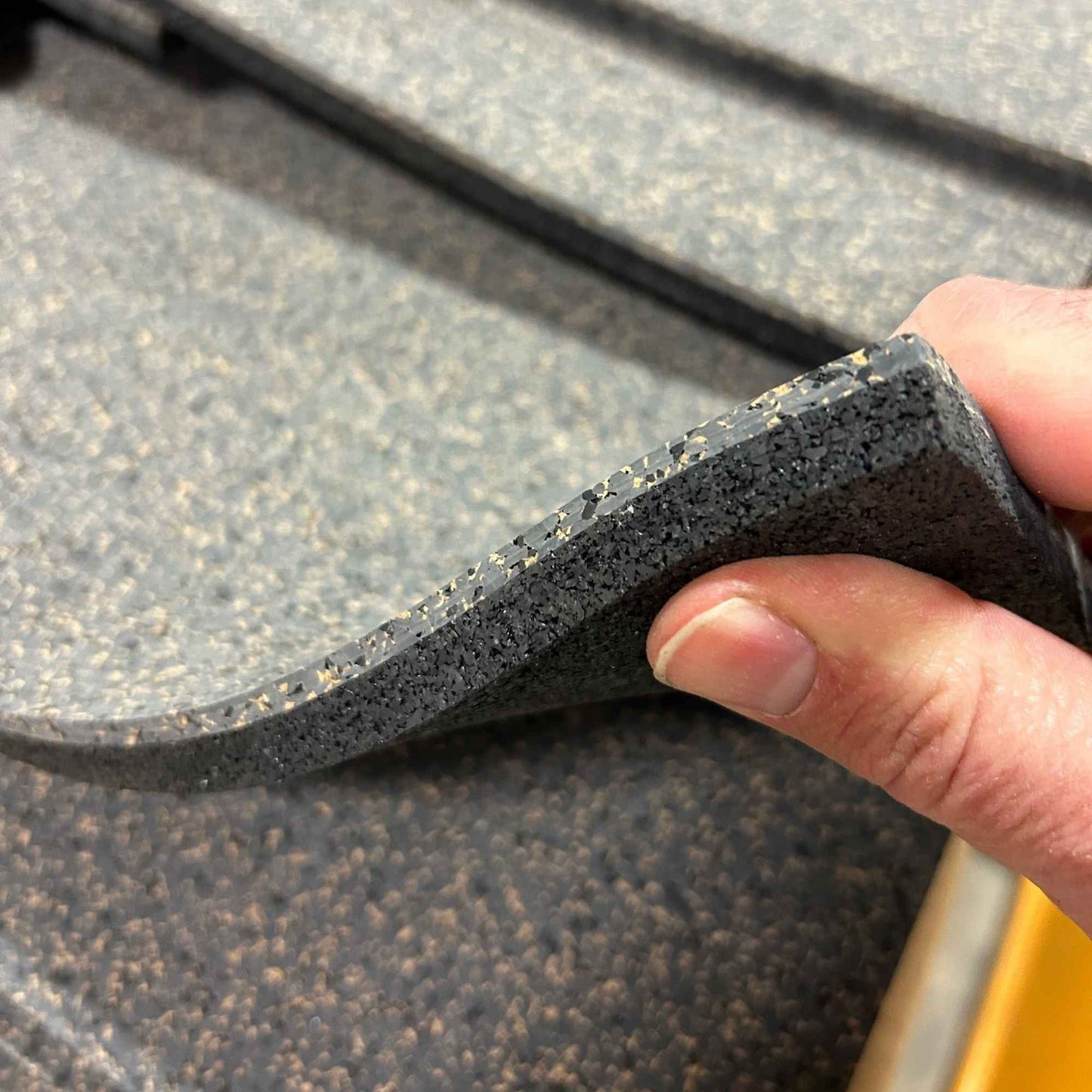 Close up of the corner of Boulder rubber cork floor featuring a charcoal grey base color with speckles of black, and cork tan.