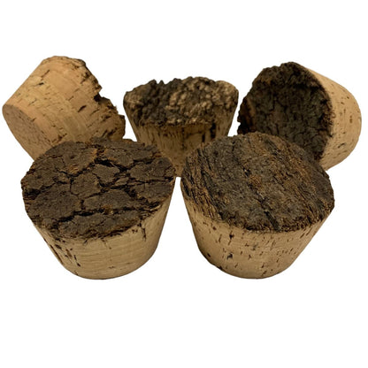 Five natural cork plugs of varying sizes and textures, showing both the dark brown, rough texture outer cork and the light tan, smooth inner cork