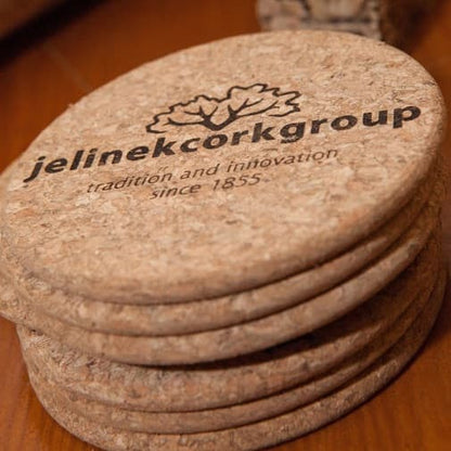 Stack of round solid cork coasters with Jelinek Cork Group logo laser-engraved on the front.