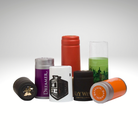 Collection of preformed custom shrink caps with various designs and colors on a white background. 