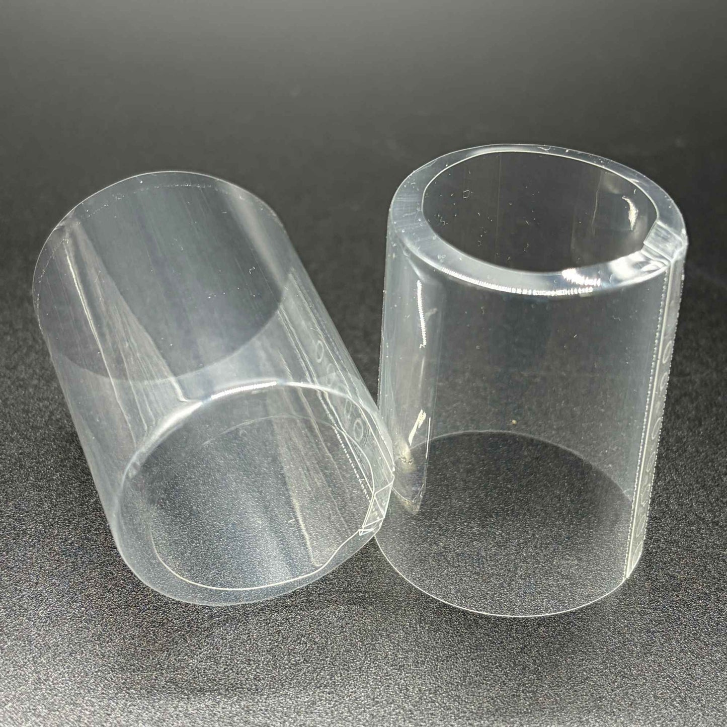 Two open cap PVC shrink caps with vertical perforation, close-up view.